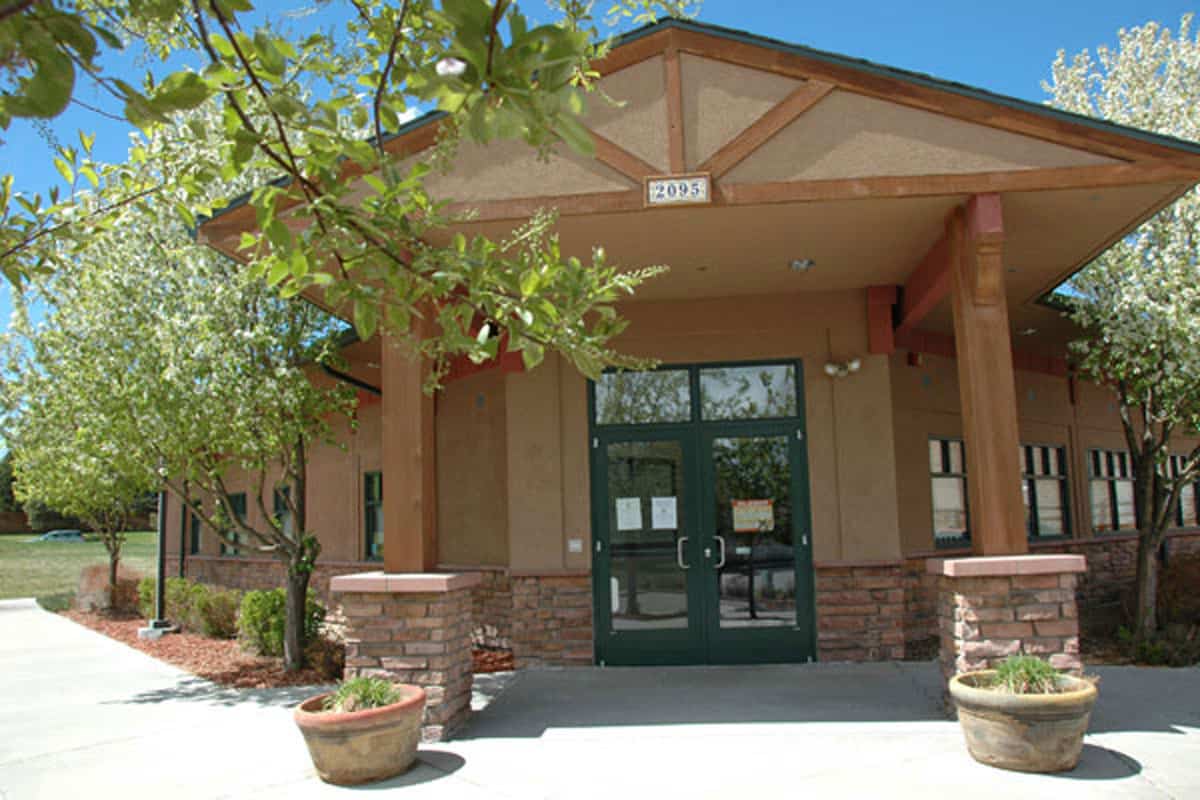 The front entrance of Kipling Veterinary Hospital at 2095 South Oak St: a stucco building with a timber gable, green double doors and flowering trees